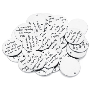 Close-up of silver stainless steel round charms with Family Where Life Begins engraving