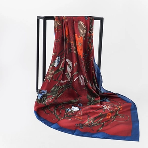 Detailed close-up of a floral satin silk scarf in burgundy with blue edges and soft drape