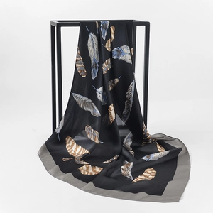 Detail of elegant satin square scarf featuring a large feather print on black fabric