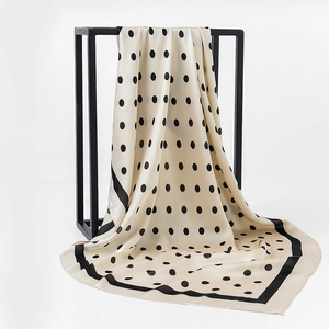 Detailed view of polka dot silk scarf draped on a minimalist black frame background
