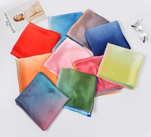 Flat lay of colorful satin silk square scarves in solid and gradient vibrant shades