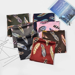 Flat lay of satin silk square scarves with colorful feather print in various elegant shades
