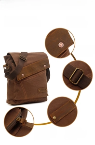 Detail of vintage canvas bag showing leather trim, brand logo, and hardware components