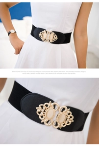 Detail of a vintage hollow-out gold buckle with inset cat-eye stones on a black wide belt
