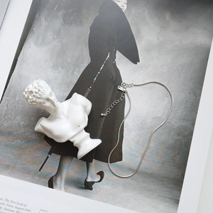 Close-up of S925 sterling silver snake bone anklet with lobster clasp on vintage magazine