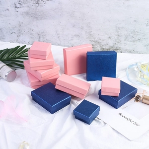 Variety of pink and dark blue kraft jewelry gift boxes arranged on white fabric