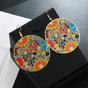 Detail of round gold-tone earrings with colorful floral oil drip patterns in a gift box