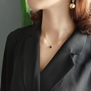 Close-up of a 925 silver gold necklace featuring a dark blue round stone pendant