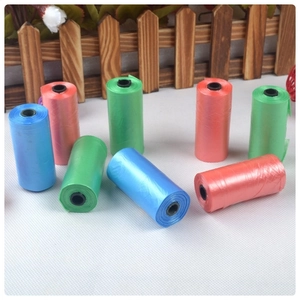Close-up of biodegradable dog waste bags in blue, green and pink rolls on white surface