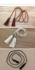 Detail view of woven waist ropes in brown, white and black with long fringe tassels