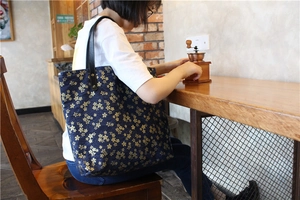 Détail du sac fourre-tout en toile marine avec motifs cerisiers dorés et bandoulière cuir
