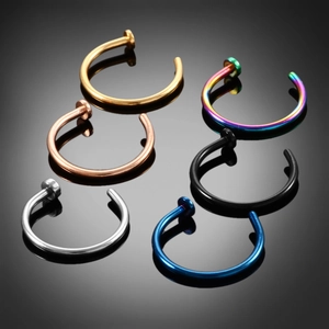Set of six colorful stainless steel C-shaped nose rings and lip hoops on dark reflective surface