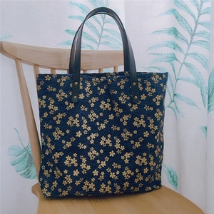 Gros plan d'un sac cabas japonais bleu marine avec fleurs de cerisier et anses en cuir