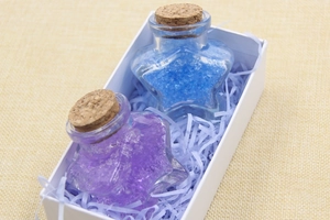 Star-shaped glass bottles with blue and purple crystals in a gift box with shredded paper