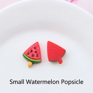 Close-up of small resin watermelon popsicle charms on a white ceramic plate