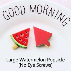 Detail of large resin watermelon popsicle charms for DIY jewelry making on white plate