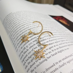Elegant 925 silver gold star and moon earrings with crystals on an open vintage book