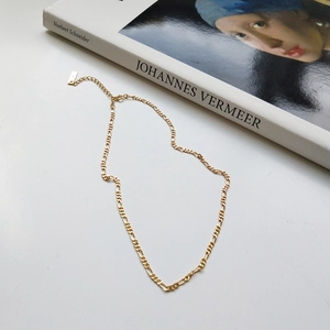 Detail of 925 sterling silver gold Figaro chain necklace on an art book background