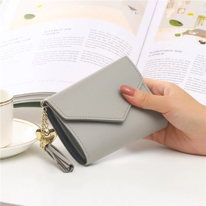 Short light gray PU leather wallet with tassel and gold heart charm in hand