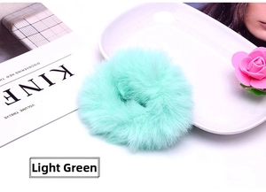 Detail shot of a soft plush light green scrunchie made of faux rabbit fur hair tie