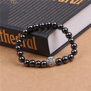Détail d'un bracelet en hématite à perles avec breloque tête de lion sur un livre ancien