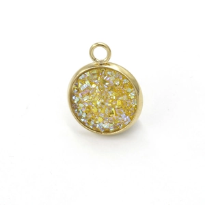 Detail of round golden stainless steel pendant with sparkling yellow resin inlay