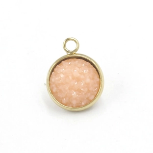 Macro detail of a 12mm gold stainless steel resin pendant with pink starry texture