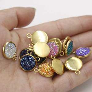 Detailed close-up of colorful round resin pendants with gold borders held in a hand