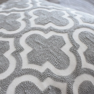 Housse de coussin nordique brodée à motifs géométriques gris sur un tissu de lin beige