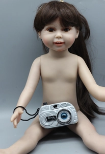 Detail of an 18 inch doll holding a silver toy camera with a black neck strap and text