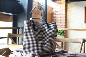 Detail of vintage gingham tote bag featuring brown check pattern and leather straps