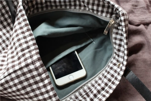 Detail view of plaid tote bag interior showing grey lining, inner pocket, and zipper
