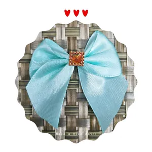 Light blue satin ribbon bow featuring a square amber rhinestone on a woven background