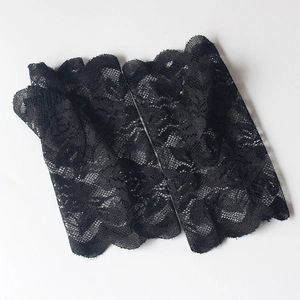 Close-up of black floral lace fingerless gloves with scalloped edges and crochet pattern
