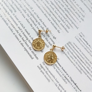 Detailed shot of gold-plated silver coin earrings with vintage portrait engraving on a book