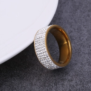 Five-row crystal paved stainless steel gold ring displayed on a white ceramic tray