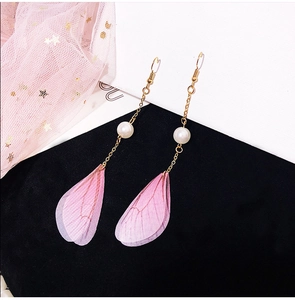 Close-up of elegant long tassel earrings with white pearl and pink butterfly wing pendant