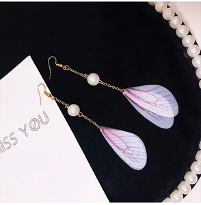 Detailed view of long gold chain earrings with pearls and translucent tulle butterfly wings