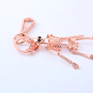 Detail view of a rose gold articulated skeleton keychain with a metallic finish on white back