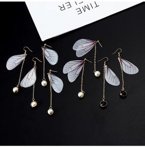 Macro detail of long cicada wing earrings with gold chain and white pearl drops