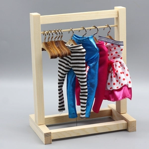 Detailed view of mini wooden clothes rack with doll pants and a red polka dot dress