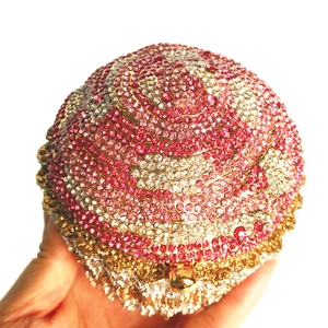 Close-up of a luxury spherical evening bag with pink and gold crystal swirl patterns