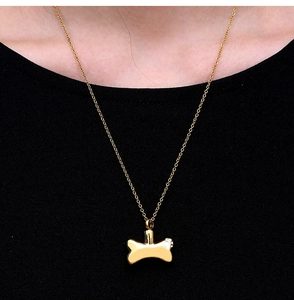 Detail view of a gold bone-shaped pendant with crystal inlay worn by a model