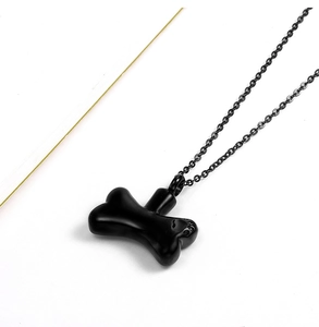 Detailed close-up of a polished black bone-shaped stainless steel cremation urn pendant