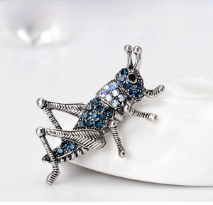 Macro view of vintage grasshopper brooch with blue and iridescent rhinestones