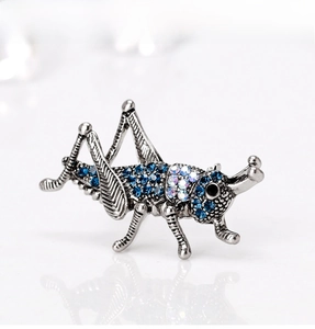 Macro detail of vintage insect brooch with blue crystals and antique silver finish