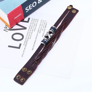 Men's dark brown woven leather bracelet with metal buckle and beads on book background