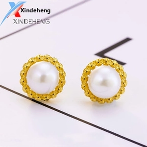 Detail of round white pearl earrings with golden sunflower textured metal settings