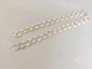 Detail of faux pearl eyewear chain with gold alloy links and white rubber anti-slip loops