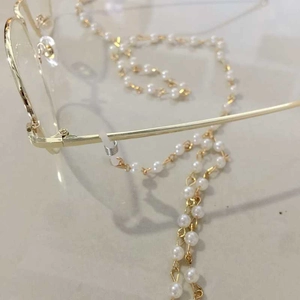 Detailed macro view of pearl eyewear chain with anti-slip silicone loop on gold frame